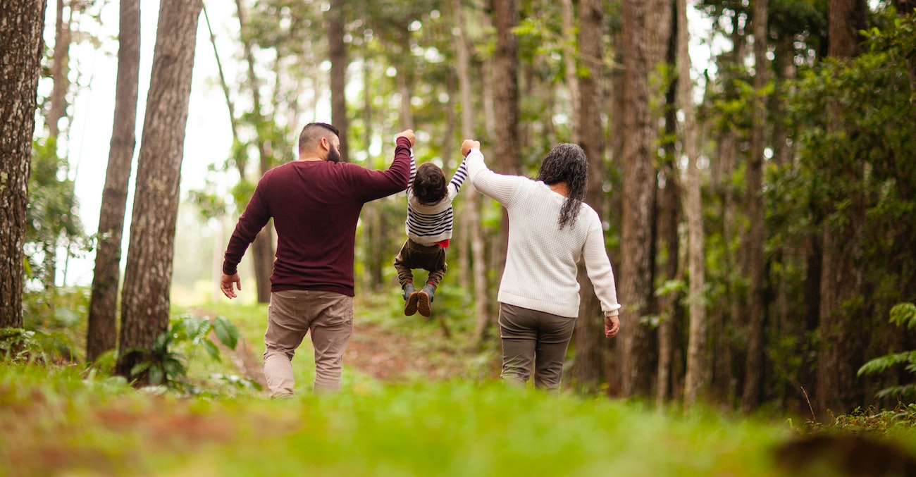 Une famille avec un père et une mère qui soulèvent leur enfant par ses bras